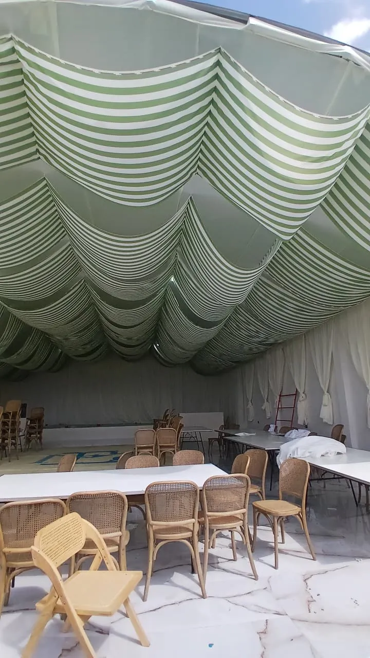 Techo de tela con rayas verdes y cortinas blancas en un salón de fiestas